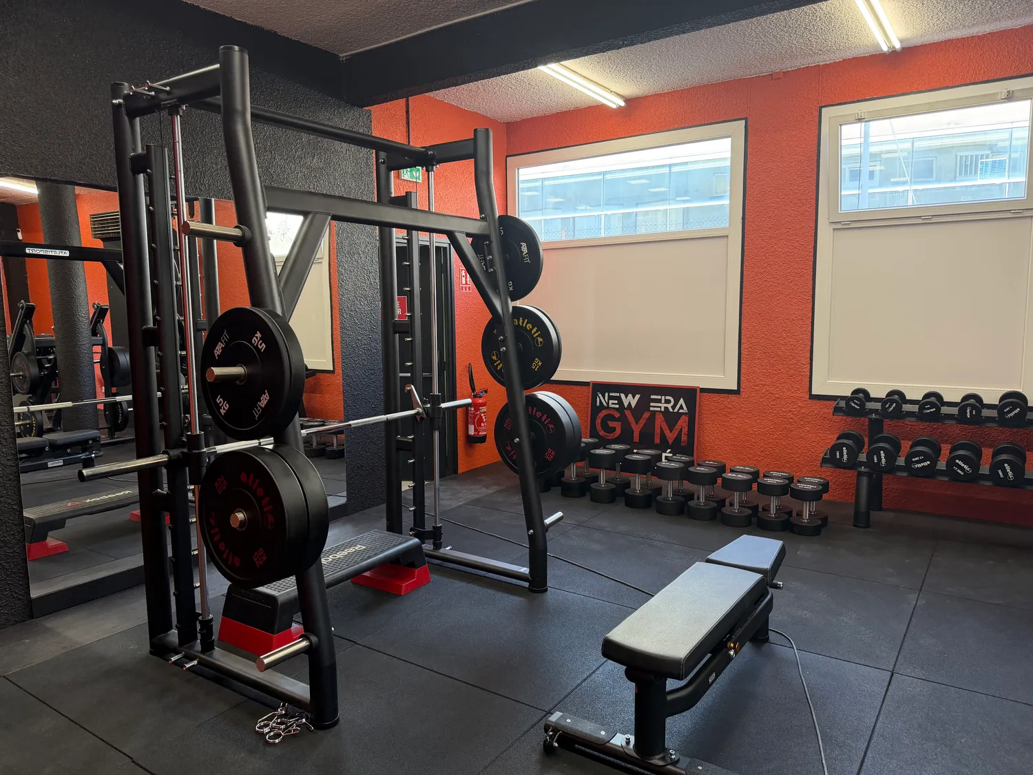 Smith machine, disques olympiques et haltères Atletisport dans la salle New Era Gym